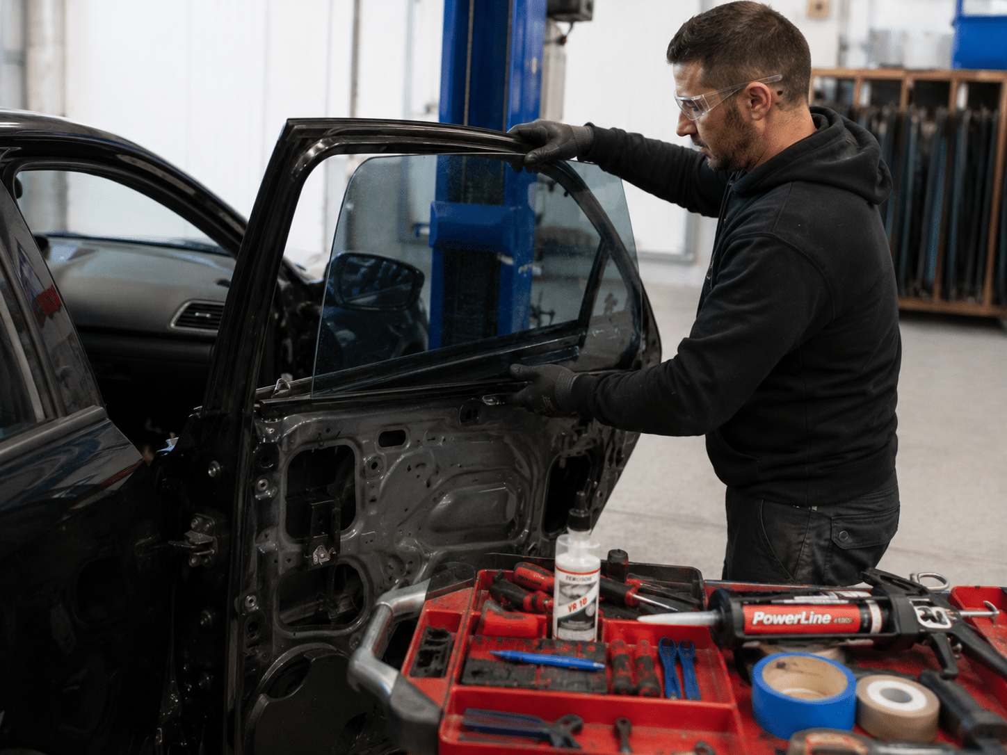 Technicien remplaçant une vitre latérale de voiture en atelier